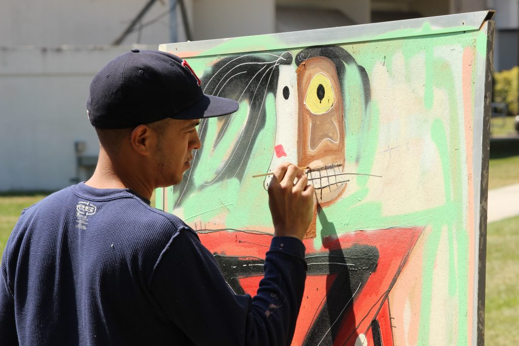 Student painting on recycled dry board.