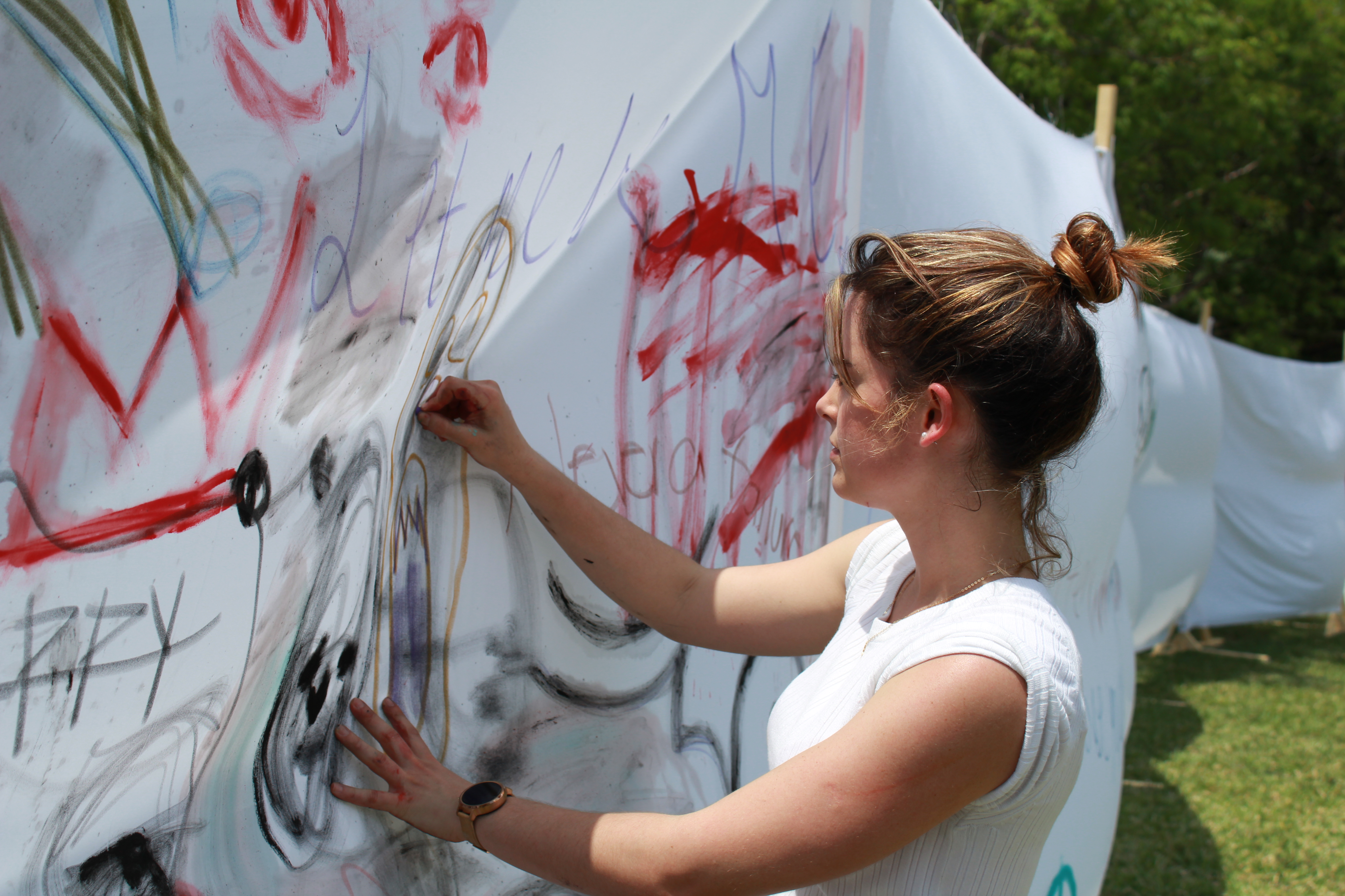 Student Stephanie Dovale painting on one the white sheets.