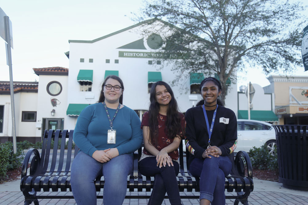 Students Franchesca Carr, Lydia Hussain and Samarah Martin sitting in front of the Historic Homestead Town Hall Museum.
