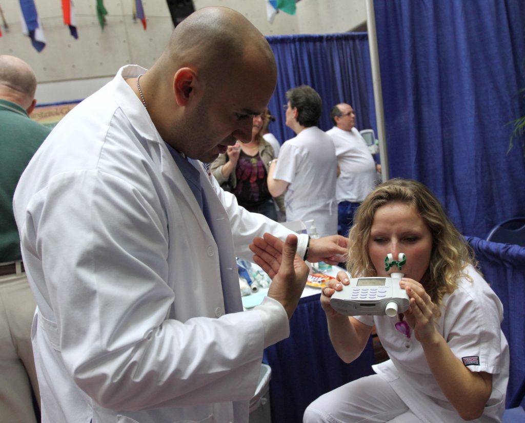 Medical student giving patient a spirometry screening test.