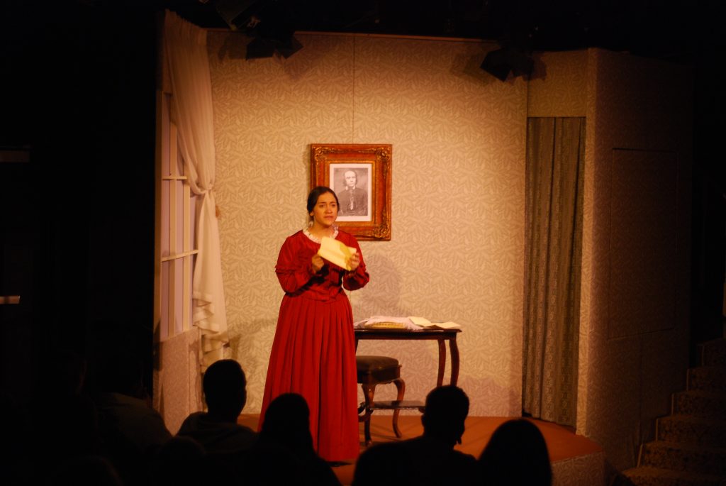 Actress performing as Emily Dickinson on stage.