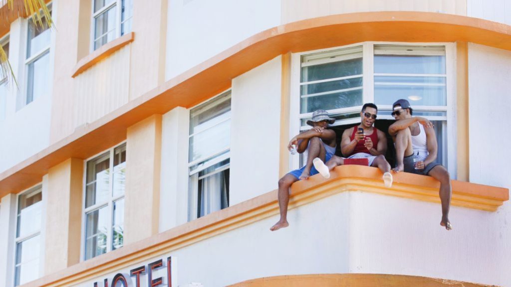 Three men sitting at their hotel window.