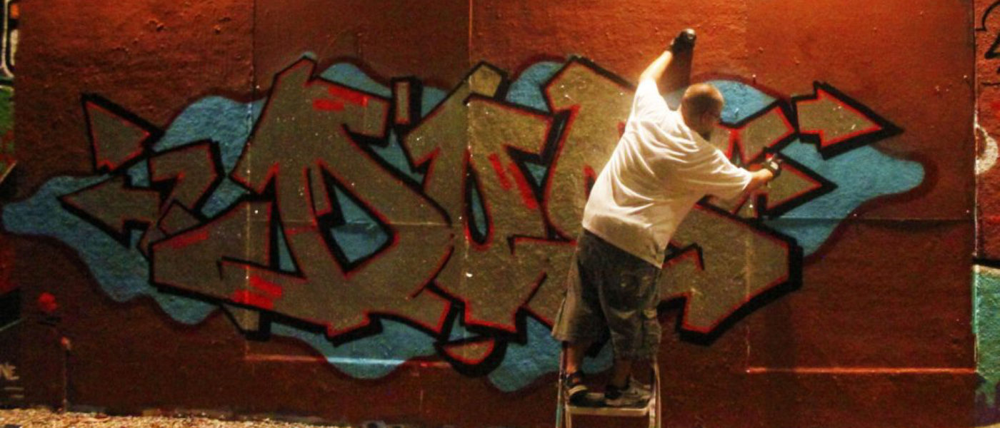 Graphic artist known as Colerizm spraying his tag on a wall.