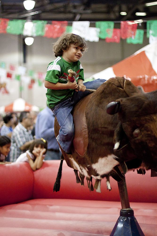 A young boy riding a mechanical bull.