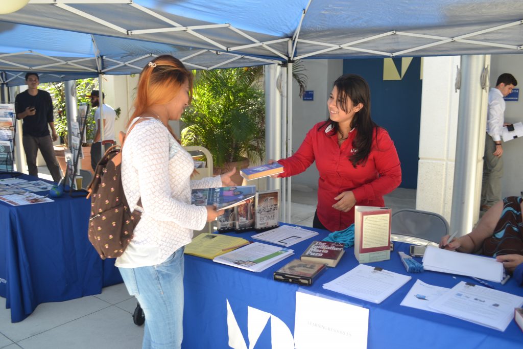 A librarian assistant handing a book to a student.