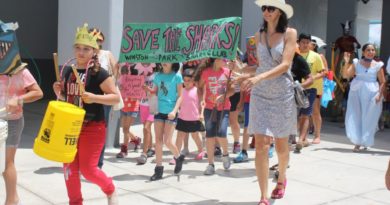 A group of children parading down with a "Save the Sharks" sign.