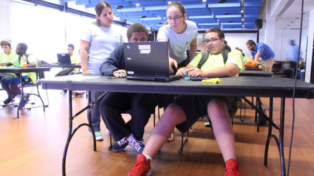 College students teaching younger students how to design and program the robot Lego NXT.