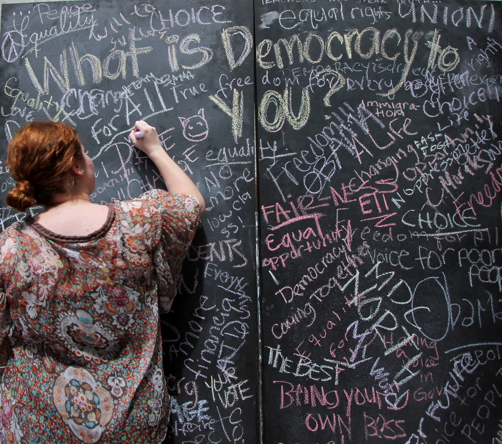 Student writing her answer to what democracy means to her.