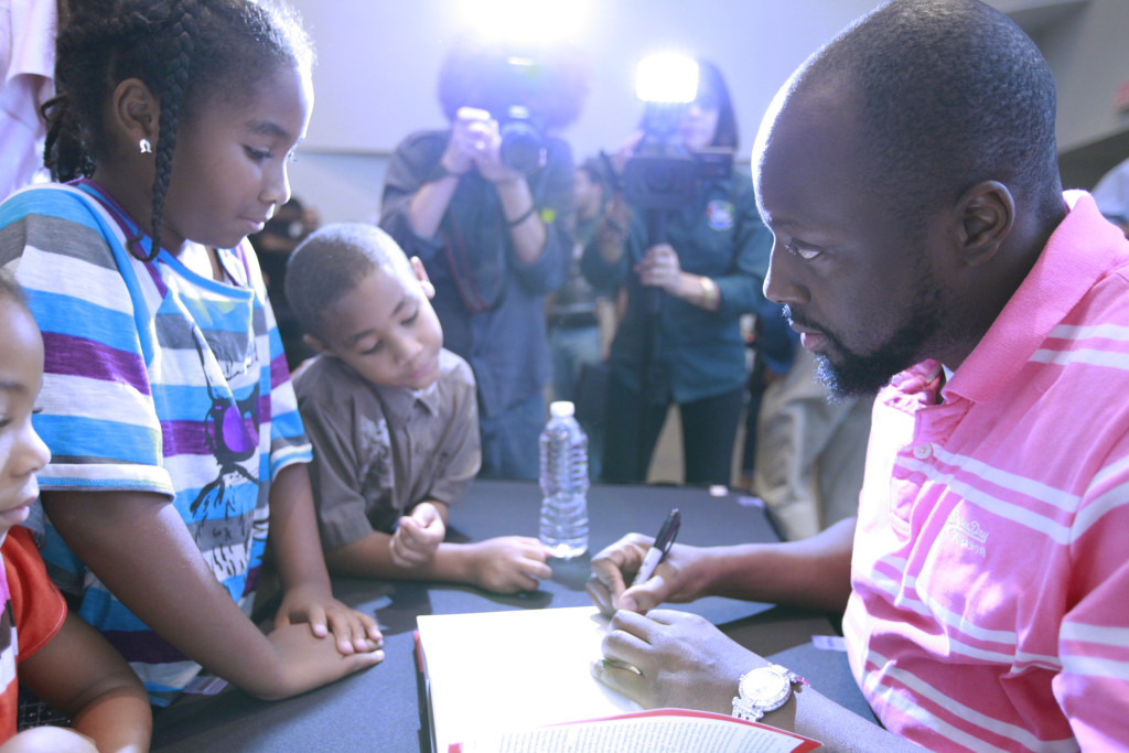 Wyclef signing his autograph for children.