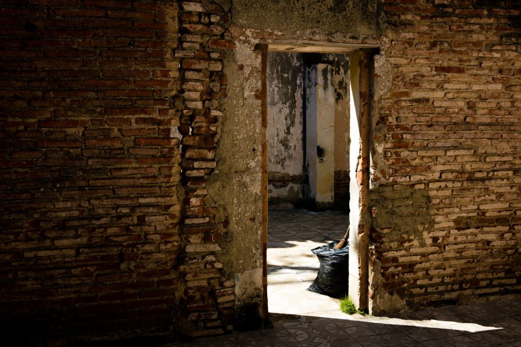 An opened door to a brick house with no roof.