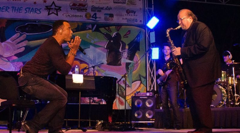 Jon Secada and Ed Calle performing on stage.