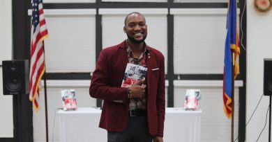 Haitian author David Frederick posing for the camera with his book.