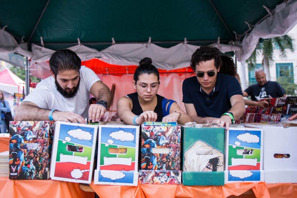 Book fair visitors looking through a crate of comic books.