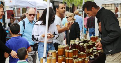 People gathering around jars of honey.