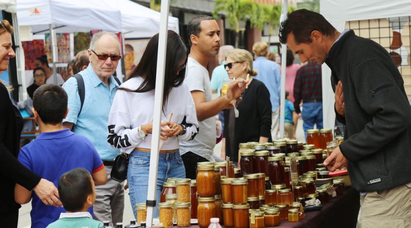 People gathering around jars of honey.