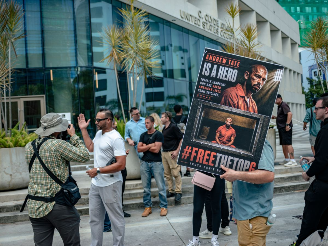 Showing Support: An Andrew and Tristan Tate supporter holds a sign outside the C. Clyde Atkins U.S. Courthouse in downtown Miami on Aug. 27. The brothers appeared for a bond hearing while fighting extradition to the United Kingdom but the appearance ended without a ruling. The brothers face 59 criminal counts including rape, human trafficking and sexual assault, allegations they deny. LUCAS DUARTE/THE REPORTER